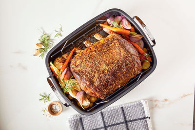 Rack of ribs cooked with aromatic vegetables in a nonstick roasting pan