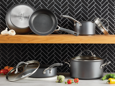 Collection of Circulon pots and pans sitting on a countertop and shelf. 