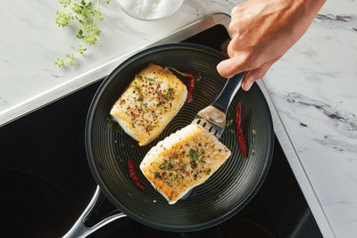 Home cook serving lightly seared whitefish cooked in a frying pan. 