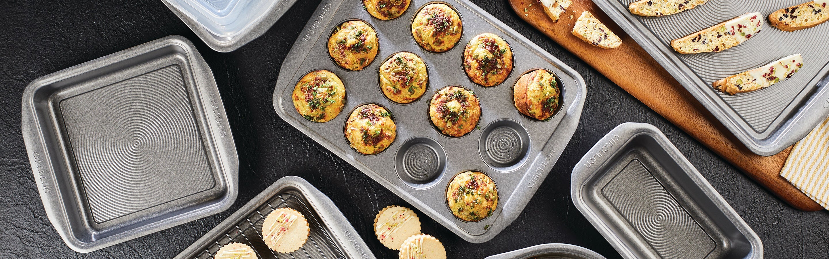 Sliced chocolate toffee bars on a cooling rack, baking pan, broken chocolate pieces, and measuring spoons on a gray tabletop.