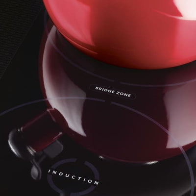 Red pot on an induction cooktop with "Bridge Zone" marking.