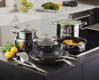Cookware set on a kitchen counter with lemons and parsley.