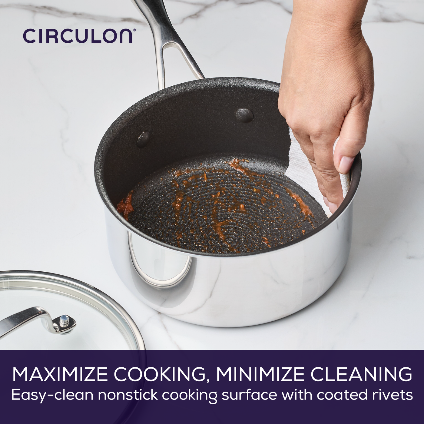 Hand cleaning a saucepan with nonstick coating on a marble surface.