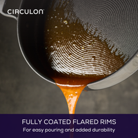 Nonstick saucepan pouring liquid with fully coated flared rims visible.