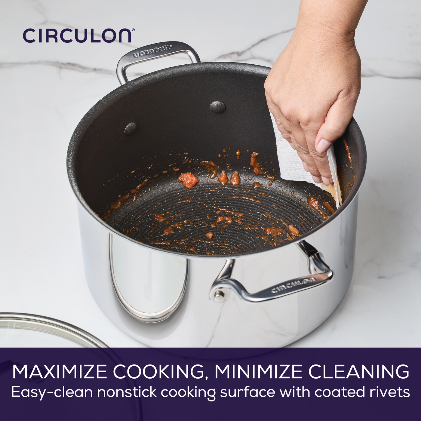 Hand wiping a nonstick pot with paper towel on a kitchen counter.