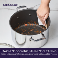 Hand wiping a nonstick pot with paper towel on a kitchen counter.