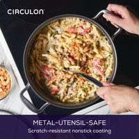 Person stirring pasta with metal spoon in a nonstick pan on a stovetop.