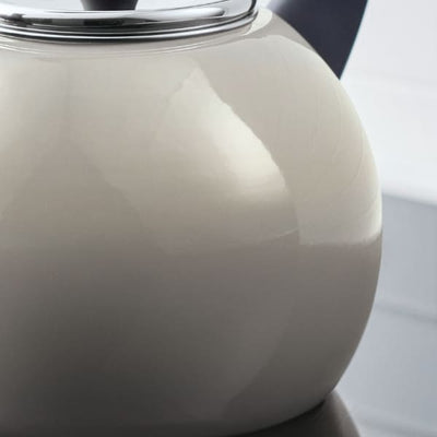 Close-up of a shiny grey kettle with a black handle and a reflective surface.