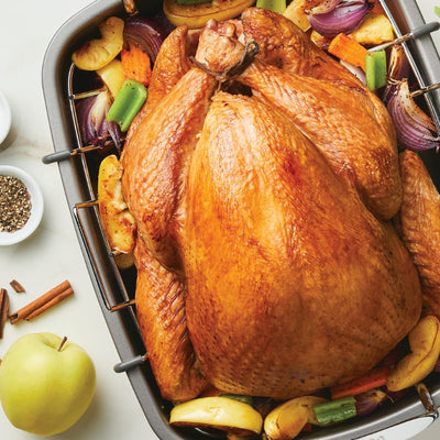 Roasted turkey with vegetables and spices in a baking tray.