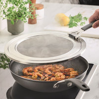 Shrimp cooking in a pan with a Universal Stainless Steel Splatter Guard.