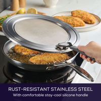 Hand holds Universal Stainless Steel Splatter Guard over sauté pan on stovetop.
