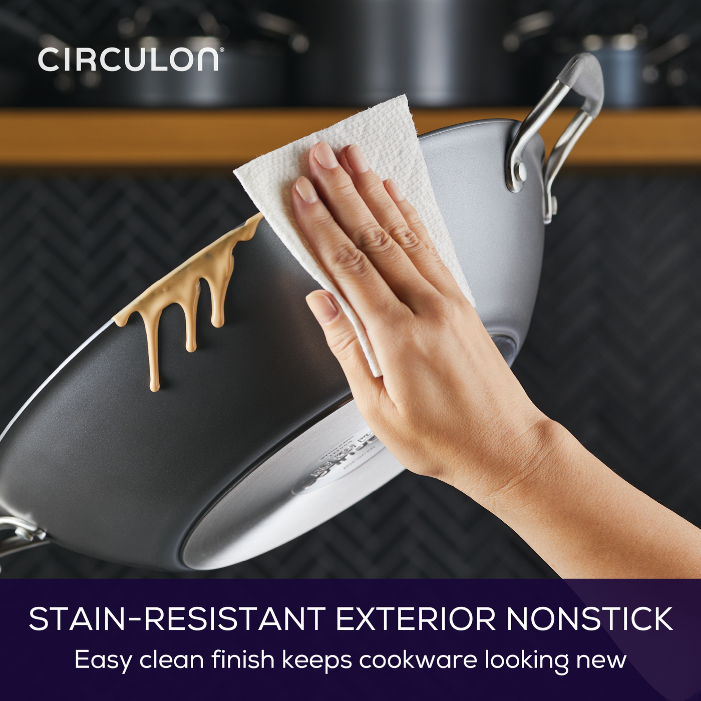 Hand wiping nonstick pan with paper towel, food residue sliding off.