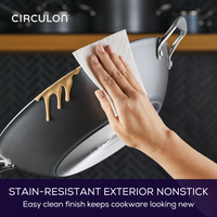 Hand wiping nonstick pan with paper towel, food residue sliding off.