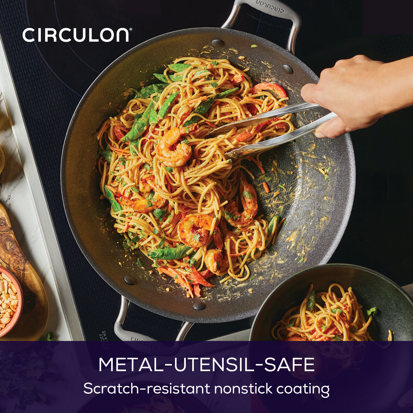 Someone cooking pasta with shrimp and vegetables in a nonstick pan.