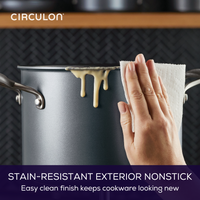 Hand wiping a nonstick pot with food spilling over the edge.