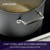 Close-up of a pot with cast steel and silicone handles on a stovetop.