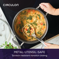 Hands holding a pot of vegetable soup on a stove with a ladle.
