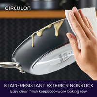 Person wiping a stain-resistant nonstick pan with a paper towel.