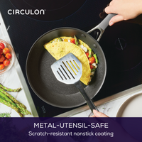 Person flipping an omelette in a nonstick frying pan on a stovetop.