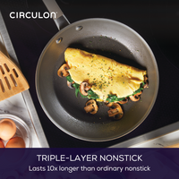 Omelet with mushrooms and spinach in a nonstick frying pan on a stove.