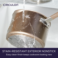 A saucepan being rinsed under a faucet with water flowing over it.