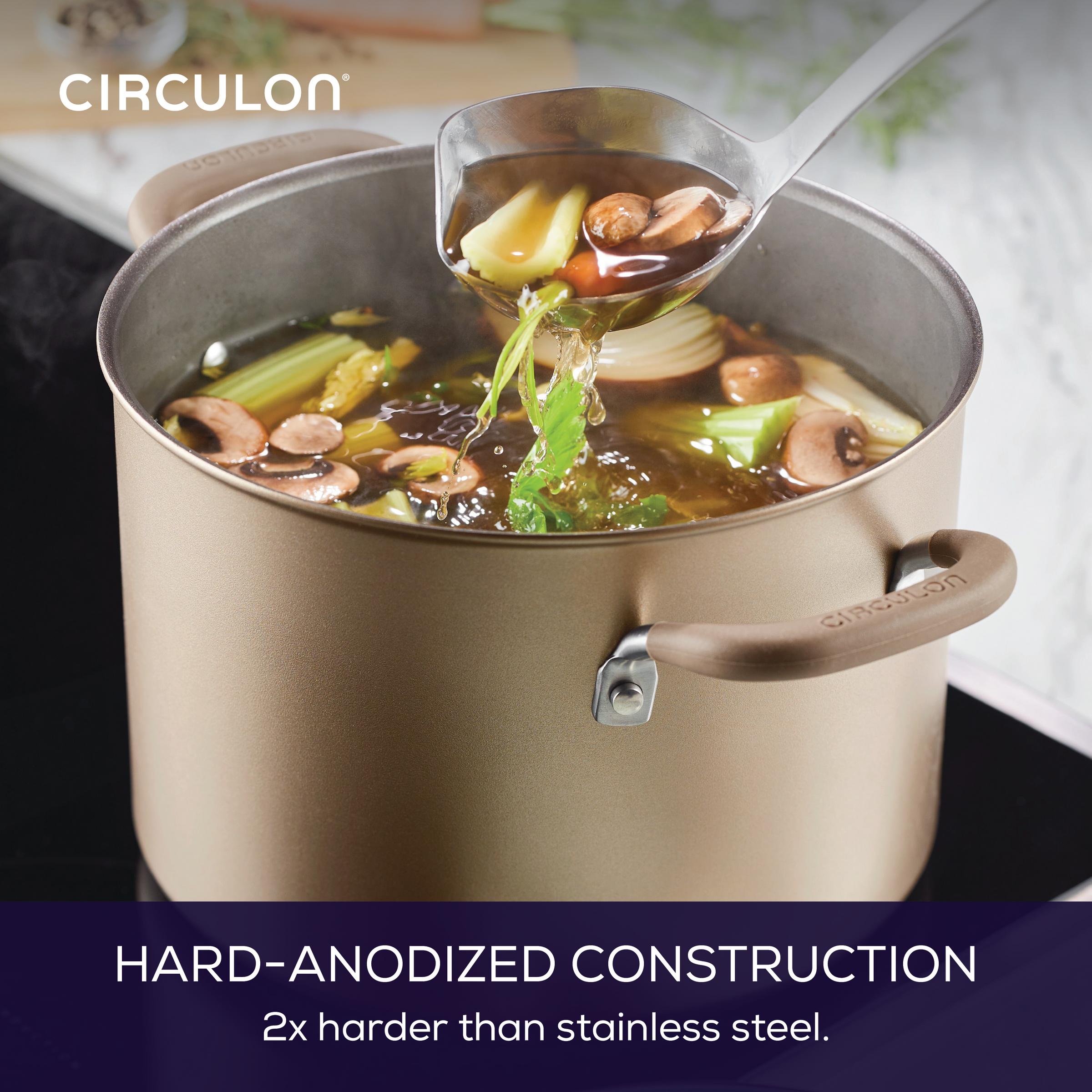 Soup being ladled from a hard-anodized pot on a stove.