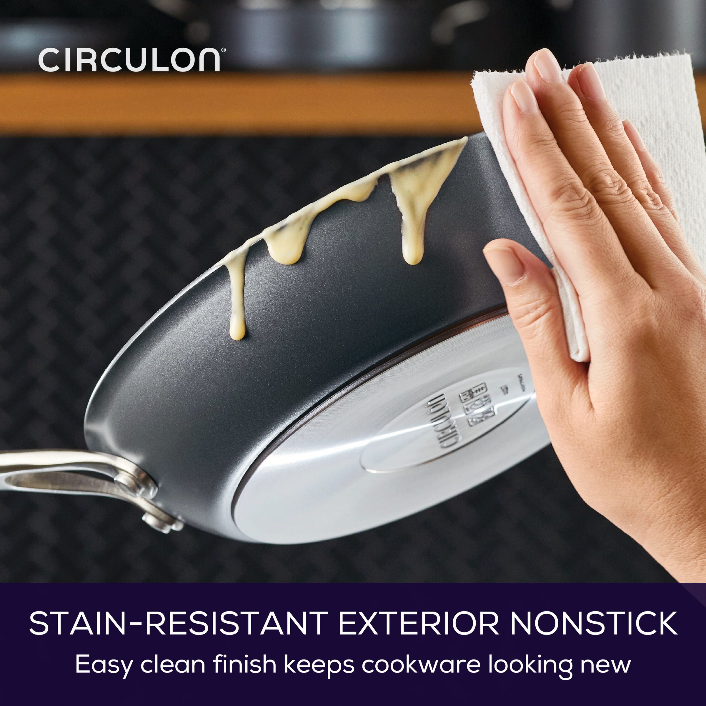 Hand cleaning a nonstick pan with a paper towel.
