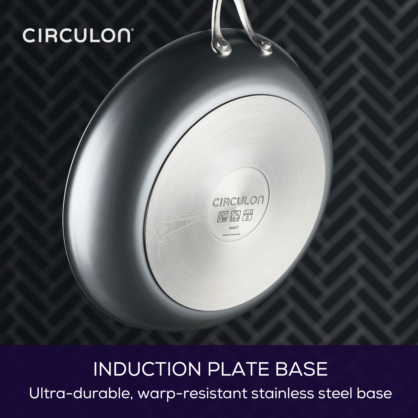 Stainless steel pan with branded induction plate base on patterned background.