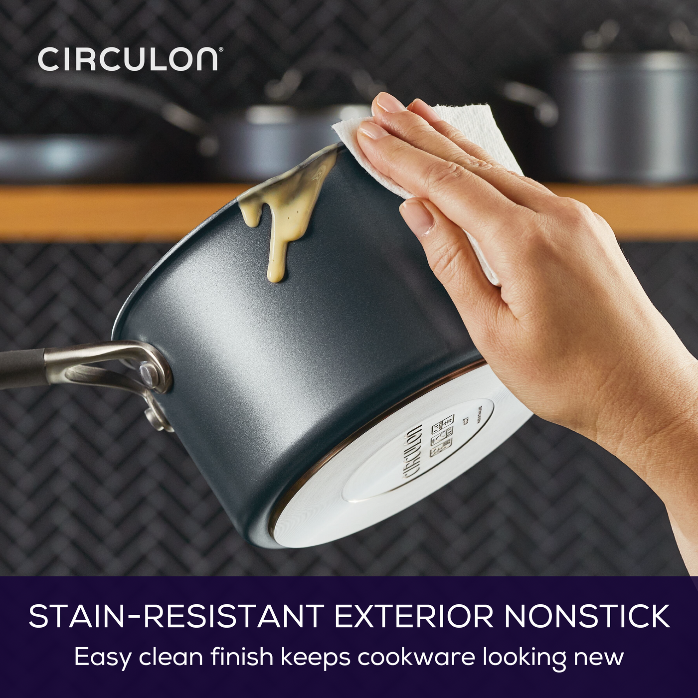 Hand wiping a pot with stained-resistant exterior nonstick surface.