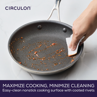 Person cleaning a nonstick frying pan with a paper towel.