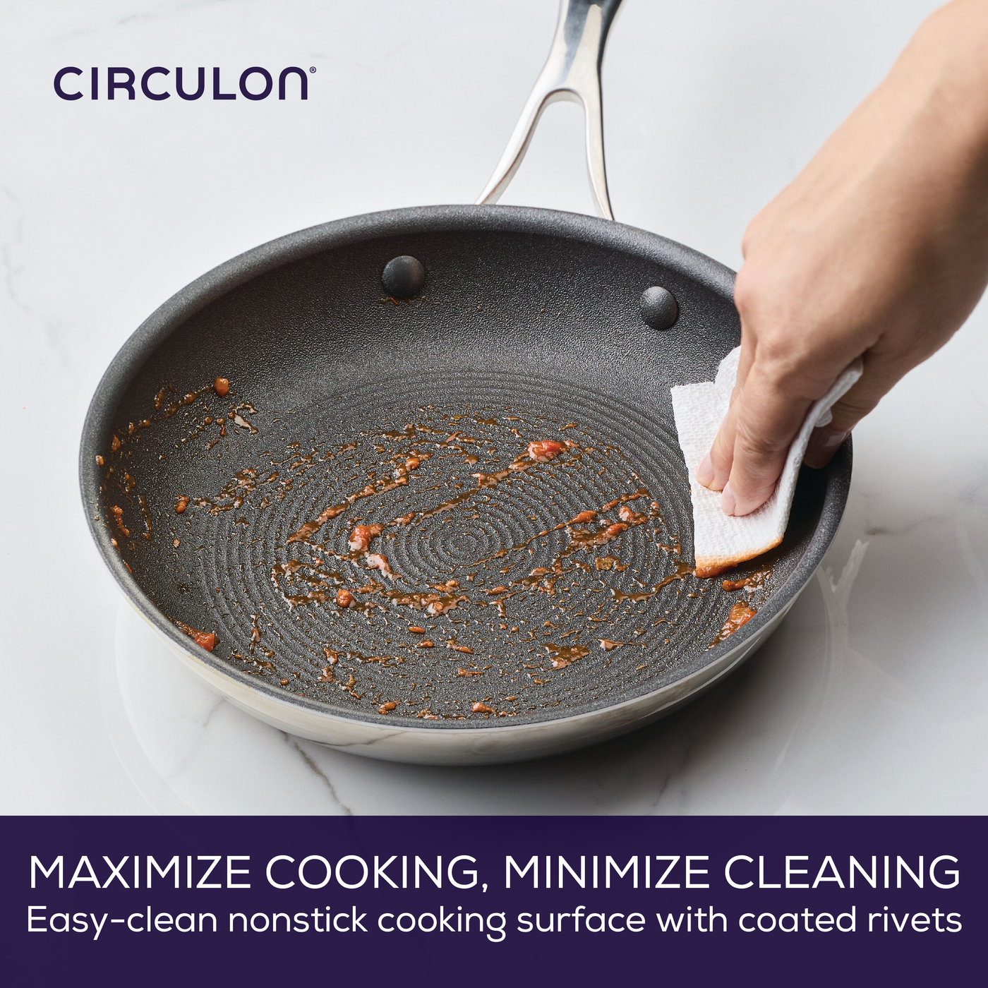 Hand cleaning a nonstick pan with a paper towel on a countertop.
