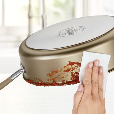 Cleaning the bottom of a pan with a cloth to remove food residue.