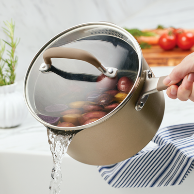 Straining water from a pot filled with potatoes on a kitchen countertop.