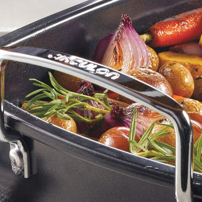 Roasted vegetables with herbs in a black pan, close-up view.