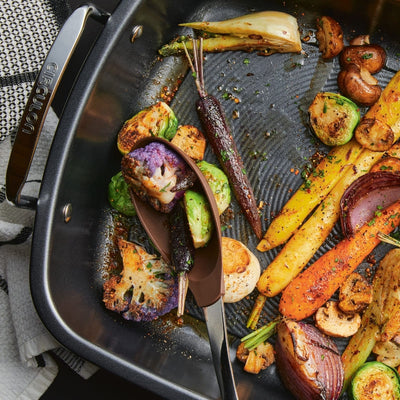 Roasted vegetables in a pan with a serving spoon.