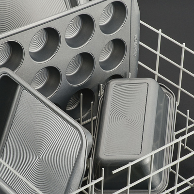Metal baking pans stacked in a dishwasher rack.