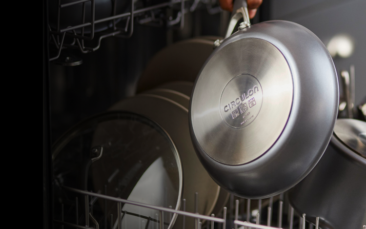 Frying pan on the background of a dishwasher, with a logo on the bottom