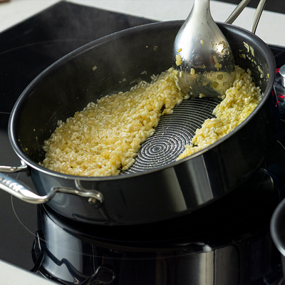 Cooking creamy risotto in a large nonstick pan on a stovetop.
