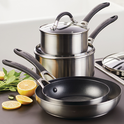 Stack of stainless steel cookware with a frying pan and cut lemons nearby.