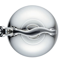 Overhead view of a shiny stainless steel kettle lid and handle.