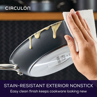 Hand cleaning nonstick pan with paper towel and removing stains.
