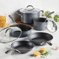 A set of gray cookware on a kitchen counter with vegetables and lemons.