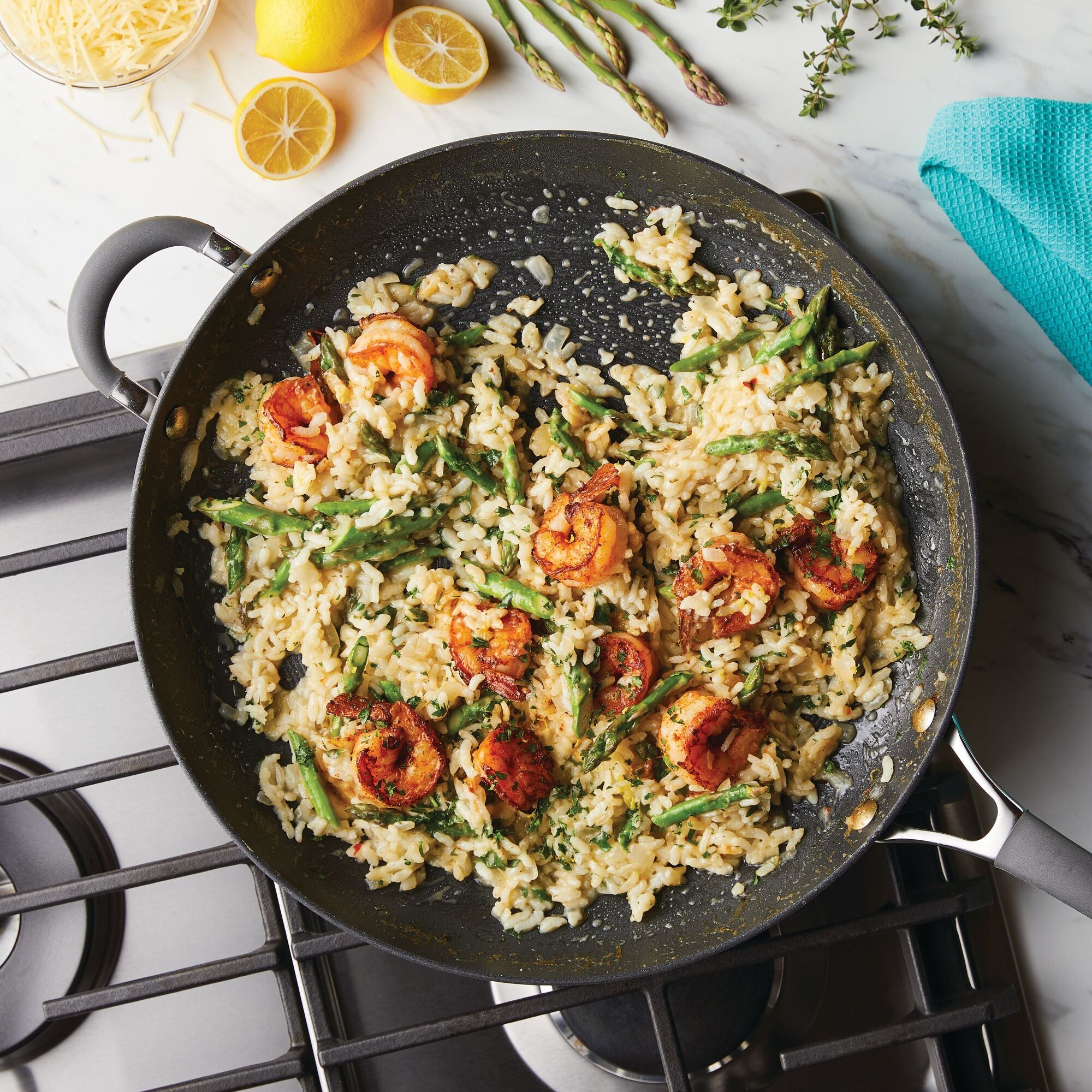 Shrimp and asparagus risotto cooking in a pan on a stove.