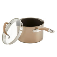 Bronze pot with glass lid slightly ajar, featuring beige handles.