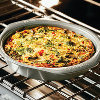 Vegetable frittata in a round pan on an oven rack.
