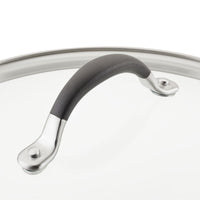 Close-up of a pot lid with a black handle and metal accents.
