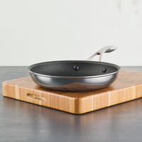 A frying pan on a wooden cutting board on a dark countertop.
