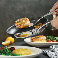 Hands transfer cooked food from a pan to a plate.