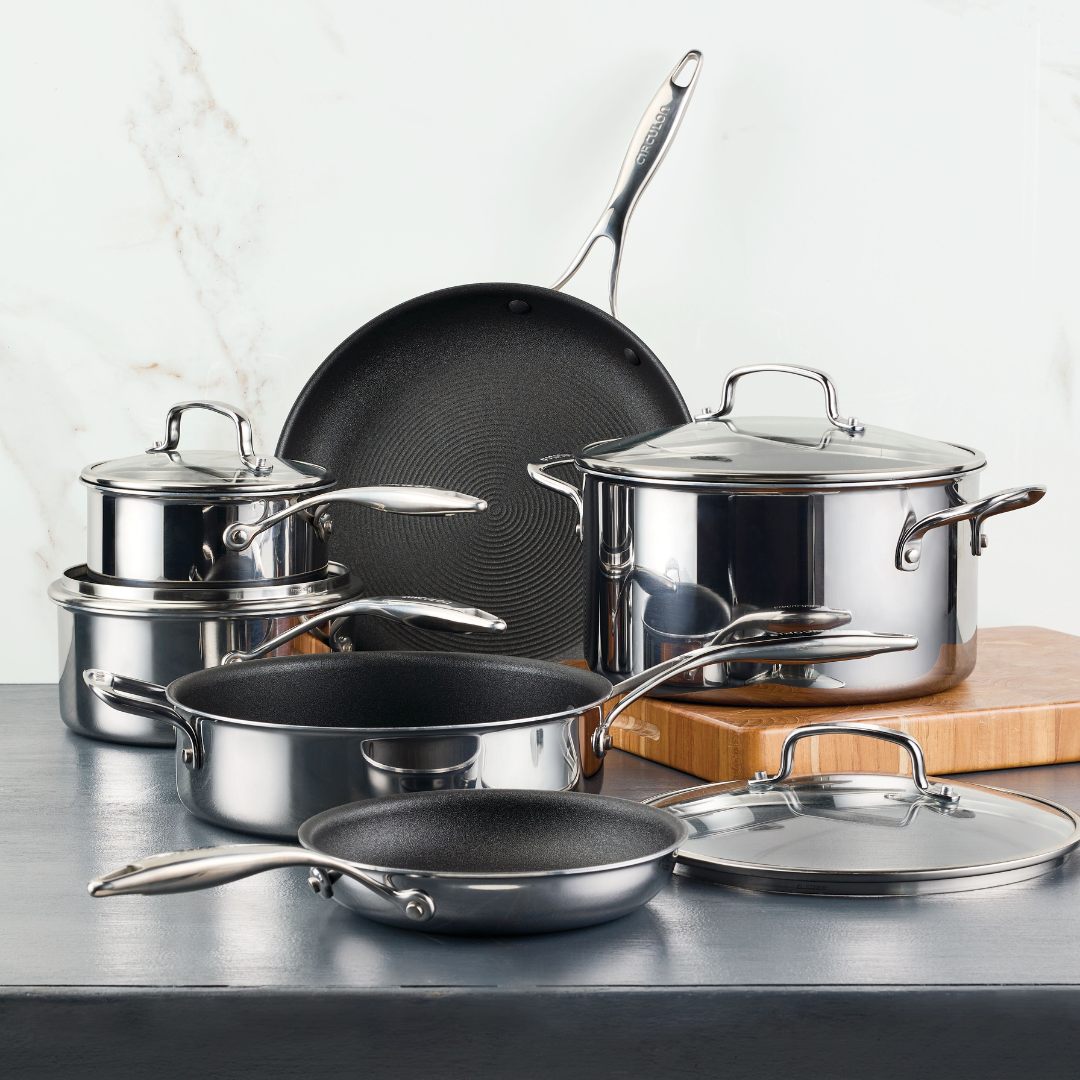 Stainless steel cookware set arranged on a dark surface.