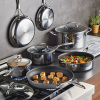 Cookware set on stove and wall; pots, pans, and food being prepared.